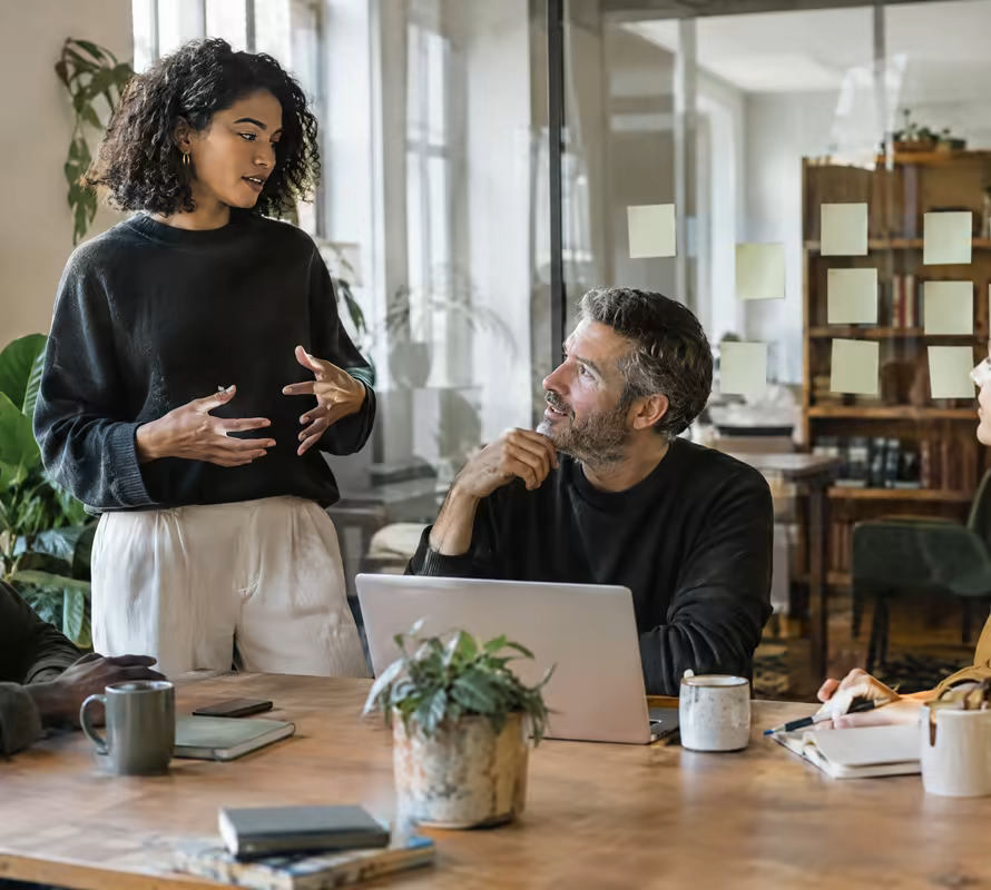 Colleagues talking around a table in a bright workspace
